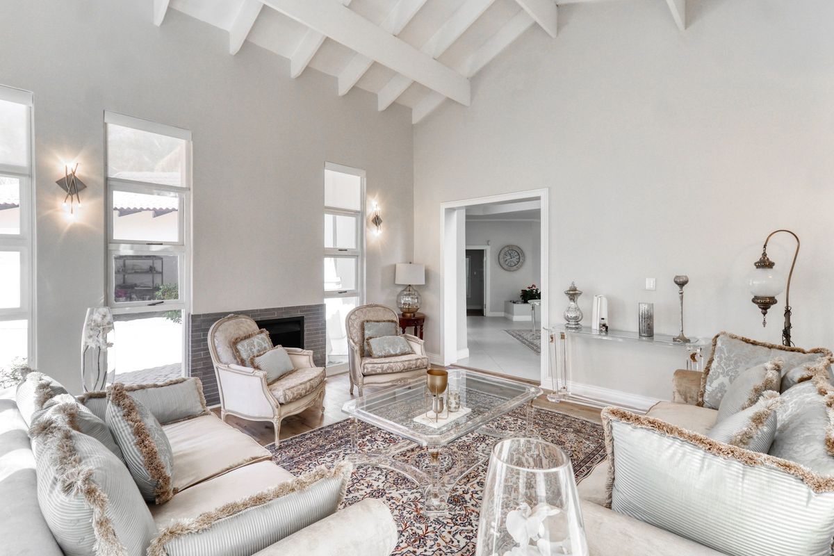 Spacious living room featuring a high vaulted ceiling with exposed beams, a fireplace, and large windows providing ample natural light.