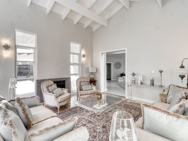Spacious living room featuring a high vaulted ceiling with exposed beams, a fireplace, and large windows providing ample natural light.