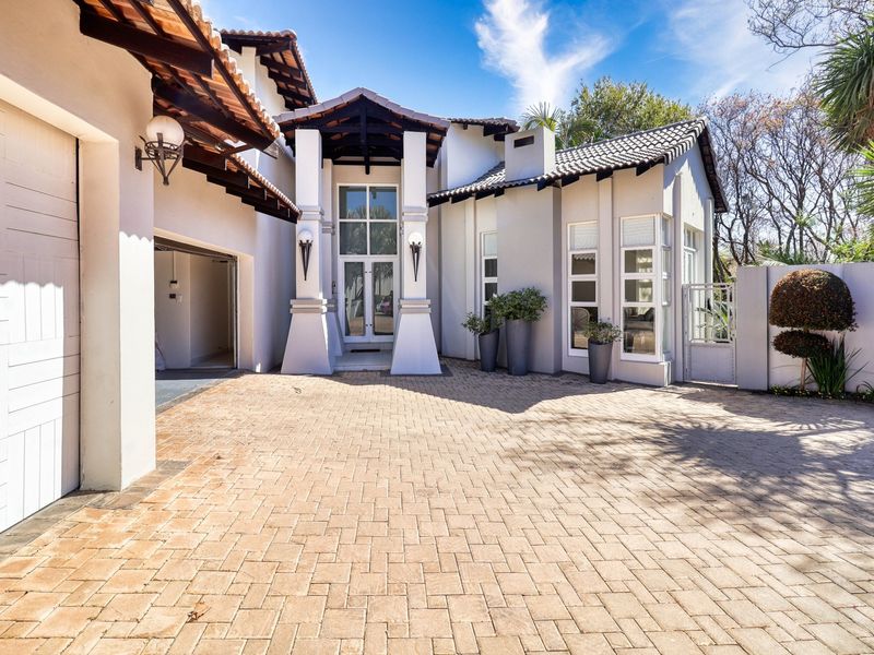 A well-maintained front facade featuring a paved driveway, double garage, and an inviting covered entrance with architectural pillar details.