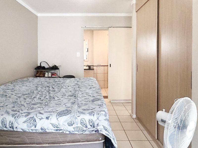 A bedroom featuring tiled flooring, a built-in sliding door wardrobe, and direct access to an en-suite bathroom.