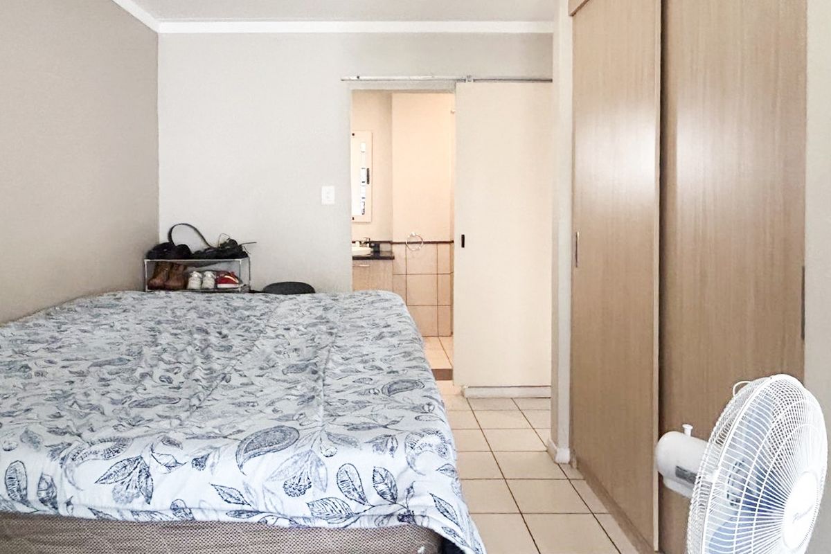 A bedroom featuring tiled flooring, a built-in sliding door wardrobe, and direct access to an en-suite bathroom.