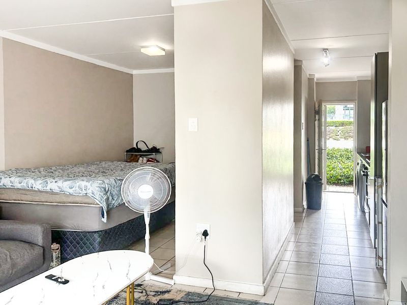 Open plan apartment layout featuring a combined living and sleeping area adjacent to a functional kitchen space with direct access to the exterior.