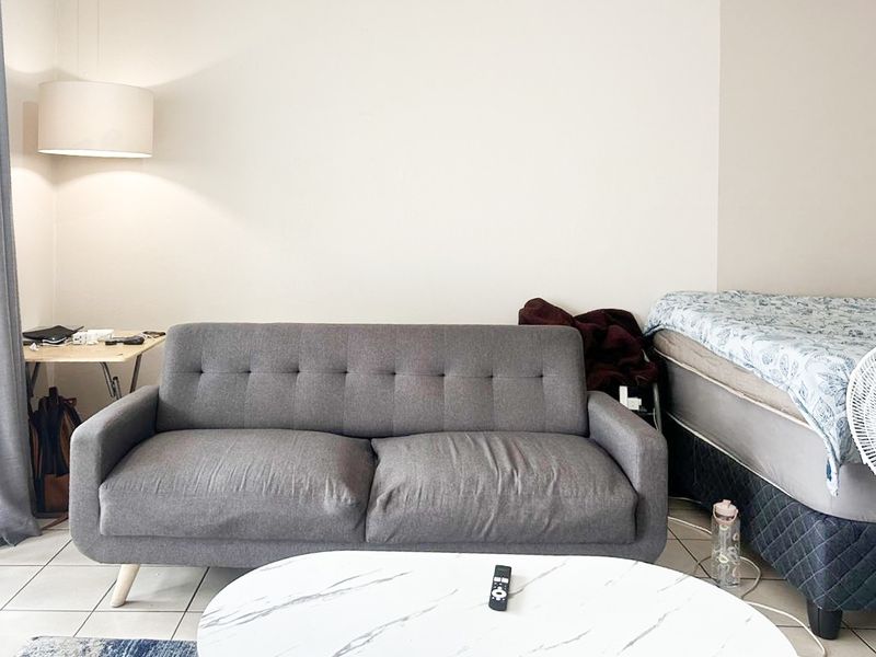A living room area featuring tiled flooring and a wall-mounted light fixture, providing a functional space for relaxation.