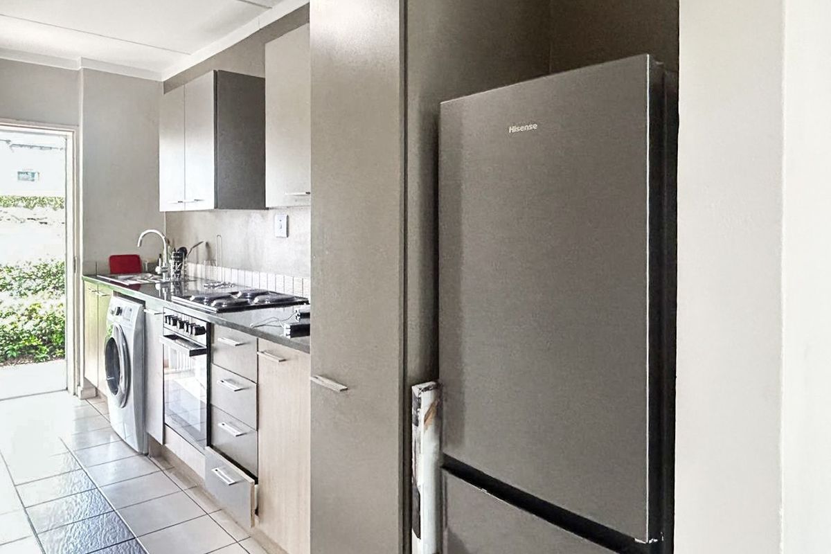 A functional kitchen featuring built-in cabinetry, a tiled backsplash, integrated oven and hob, and direct access to an outdoor area.