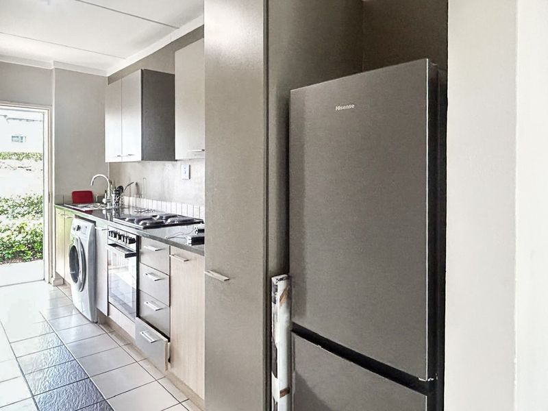 A functional kitchen featuring built-in cabinetry, a tiled backsplash, integrated oven and hob, and direct access to an outdoor area.
