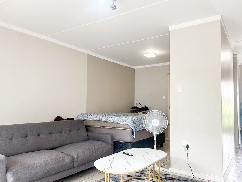 Open plan living area featuring neutral wall tones and tiled flooring, providing a versatile space for combined living and sleeping arrangements.