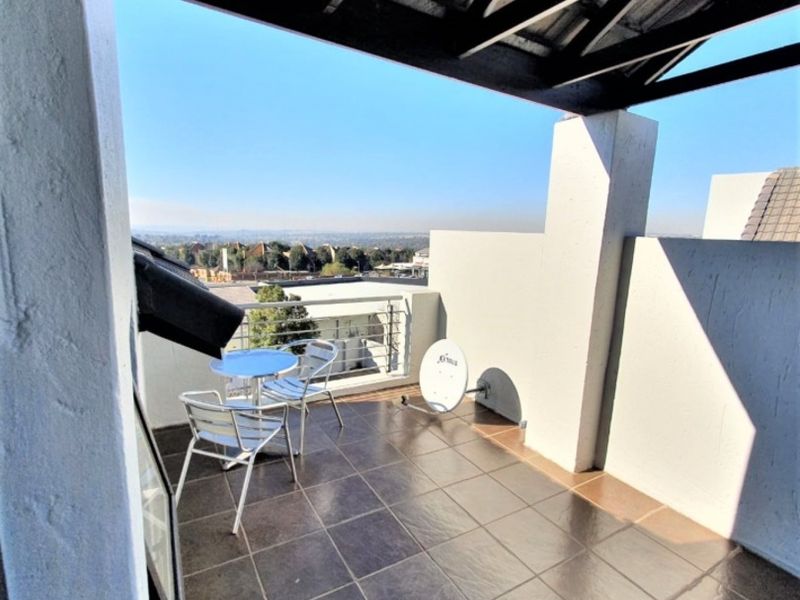 A covered balcony featuring tiled flooring and exposed timber rafters, offering an open-air space with elevated views.