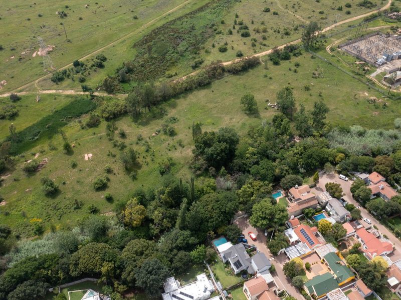 Aerial view of a large, undeveloped residential land parcel situated adjacent to an established suburban neighborhood.