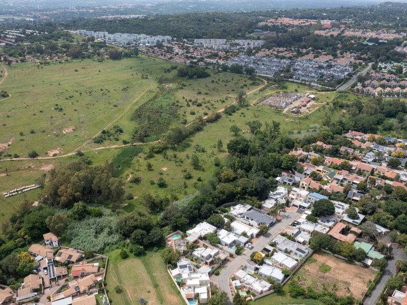 Aerial view of a large plot of undeveloped residential land adjacent to an established suburban neighborhood.