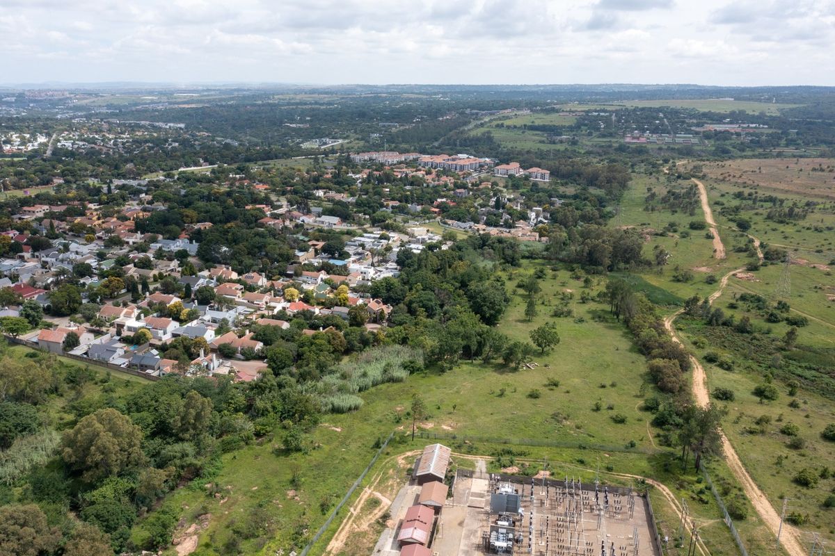 Aerial view of a residential area adjacent to an electrical substation and undeveloped green space.