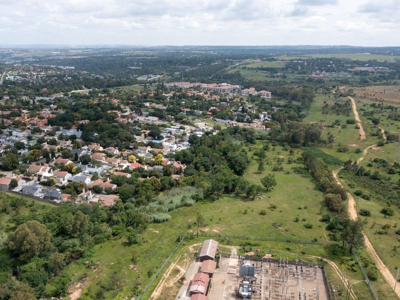 Aerial view of a residential area adjacent to an electrical substation and undeveloped green space.