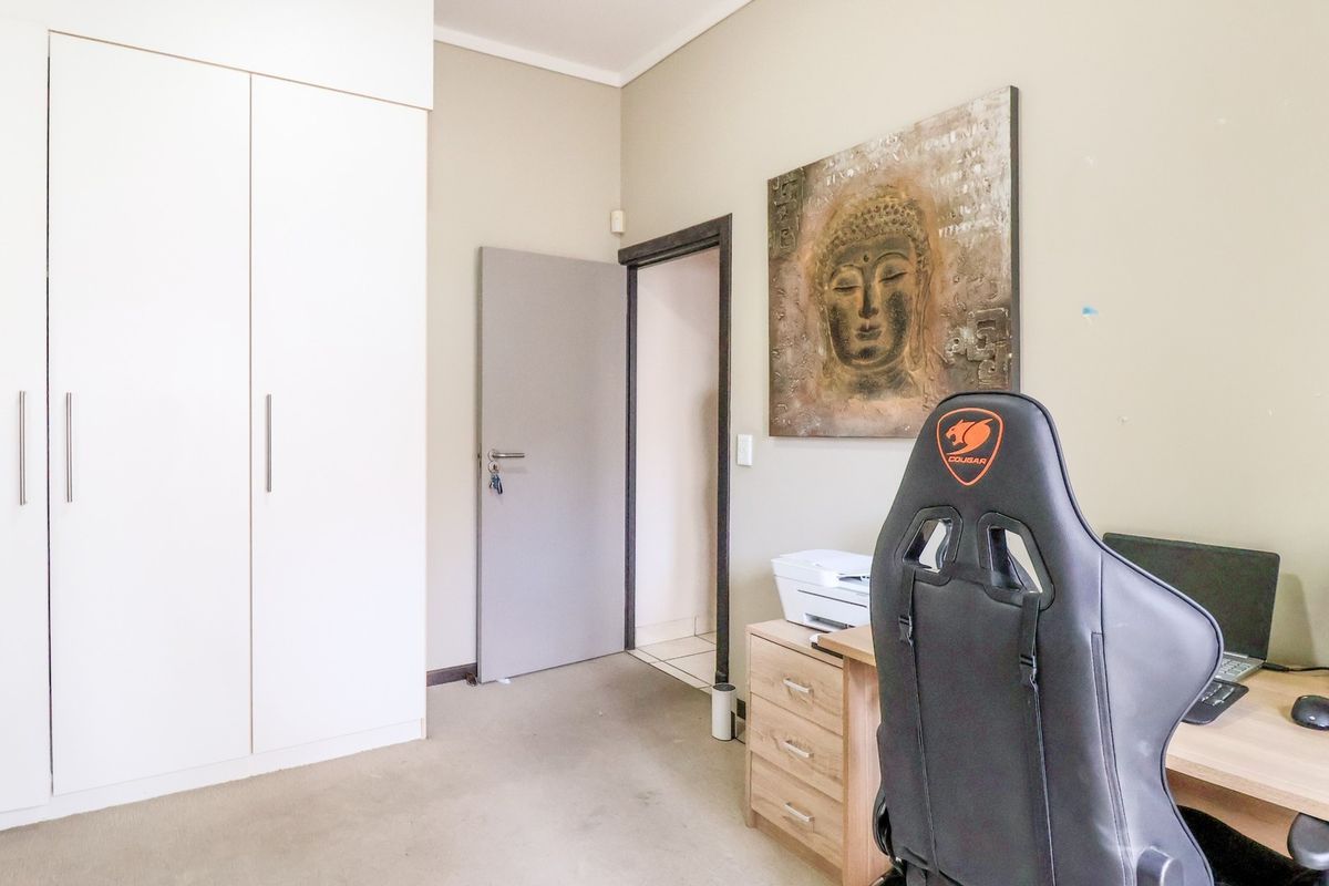 A bedroom featuring neutral wall tones, carpeted flooring, and white built-in cupboards providing ample storage space.