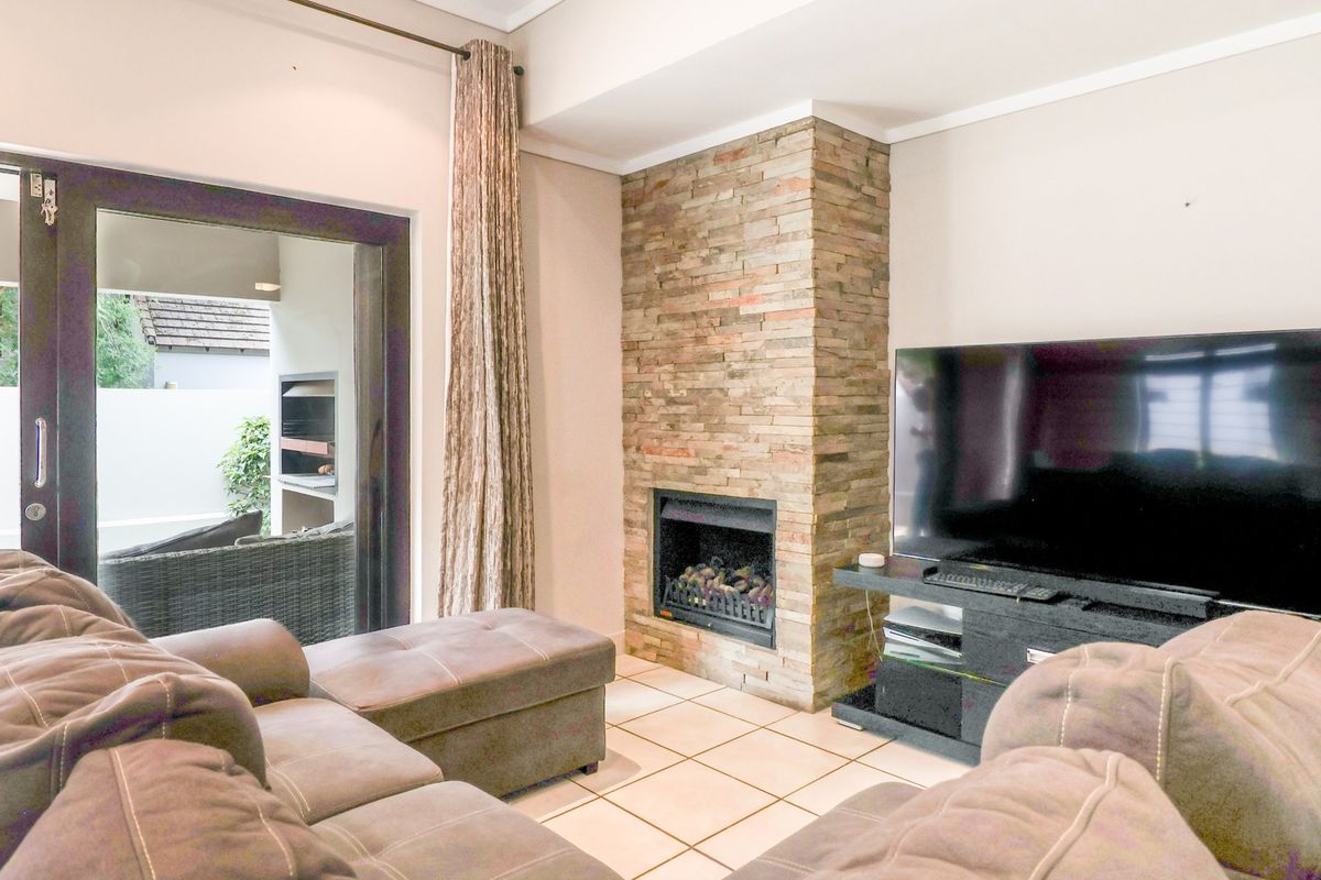 Cozy living room featuring a prominent stone-clad fireplace, tiled flooring, and direct access to an outdoor patio area.