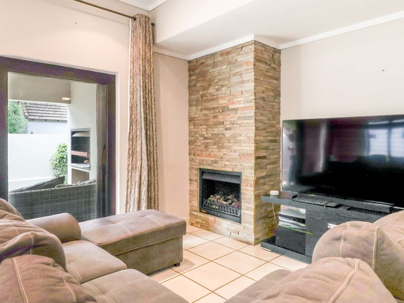 Cozy living room featuring a prominent stone-clad fireplace, tiled flooring, and direct access to an outdoor patio area.
