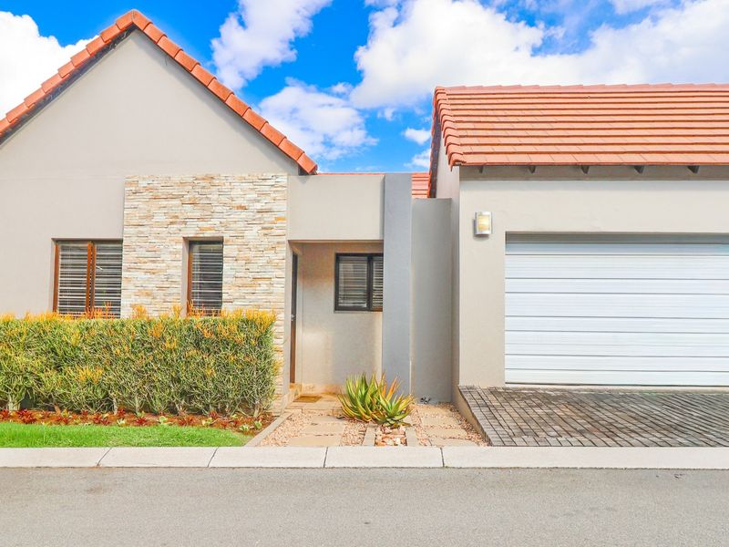 Front elevation of a modern house featuring a tiled roof, stone cladding accents, a single garage, and a neat paved entrance path.