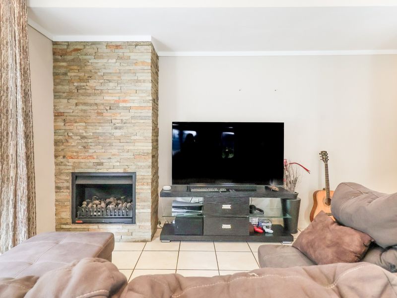 A comfortable living room featuring a prominent stone-clad fireplace and tiled flooring, providing a warm and inviting atmosphere for relaxation.