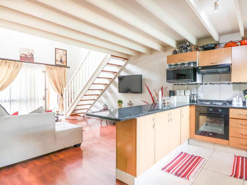 Open-plan living area featuring a kitchen with granite countertops, built-in appliances, and a wooden staircase leading to the upper level.