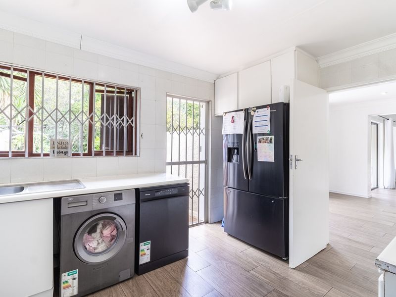 Functional laundry room featuring built-in cabinetry, a stainless steel sink, and direct access to the exterior via a security gate.