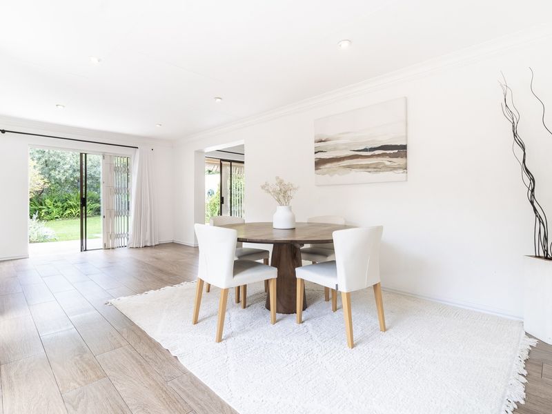 Bright and airy living area featuring wood-look tile flooring, recessed downlights, and large sliding glass doors providing seamless access to the garden.