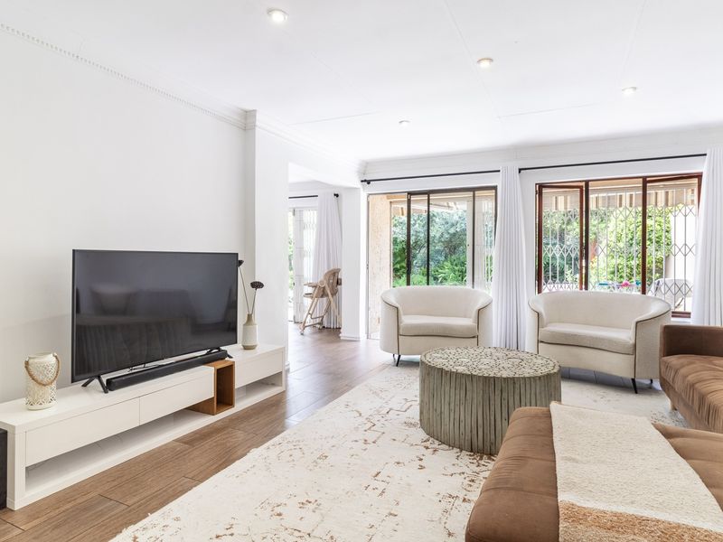 Bright and spacious living room featuring laminate flooring, recessed downlights, and large sliding glass doors providing access to the outdoor area.