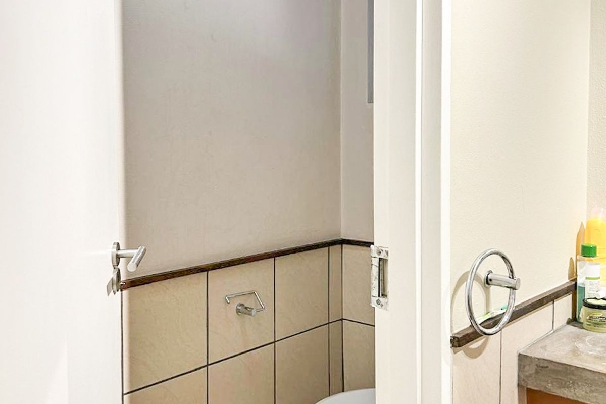 A compact bathroom featuring tiled walls and flooring, a standard toilet, and a vanity countertop with integrated towel ring.
