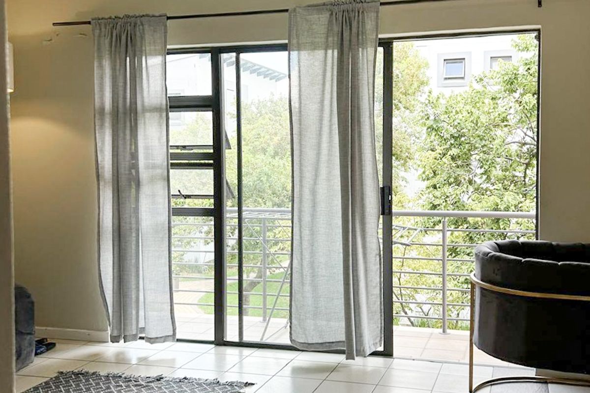 Bright living area featuring tiled floors, track lighting, and large sliding glass doors opening onto a balcony with outdoor views.