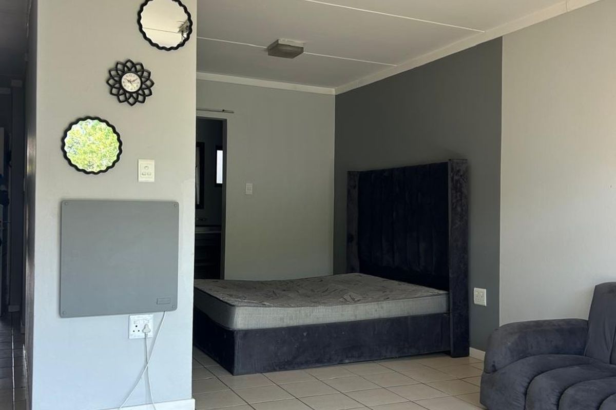 A bedroom featuring ceramic floor tiles, neutral grey wall tones, and a wall-mounted panel heater.
