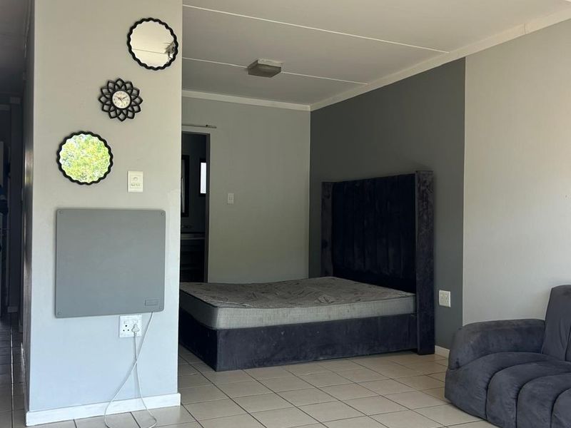A bedroom featuring ceramic floor tiles, neutral grey wall tones, and a wall-mounted panel heater.