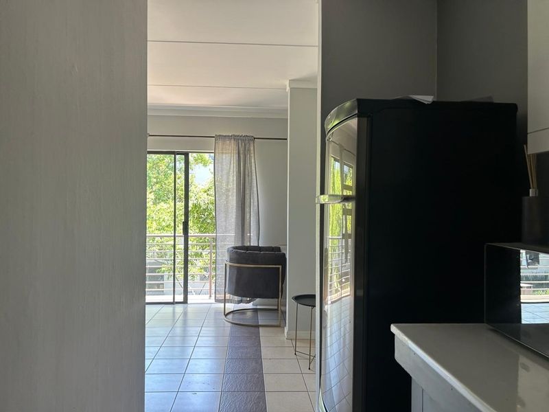 Open plan living area featuring tiled flooring and a sliding glass door leading to a balcony, providing natural light and outdoor access.