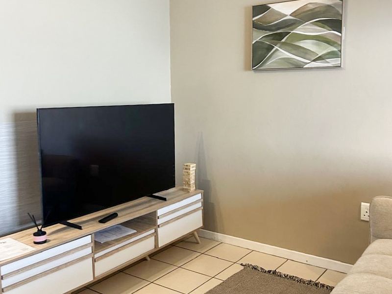 A living room area featuring neutral wall tones and tiled flooring, providing a clean and functional space.