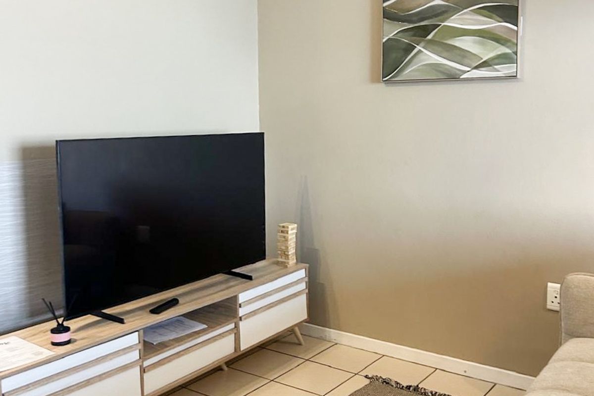 A living room area featuring neutral wall tones and tiled flooring, providing a clean and functional space.