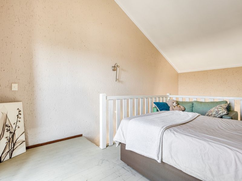 A bedroom featuring a vaulted ceiling, textured walls, and a white wooden balustrade overlooking the lower level.