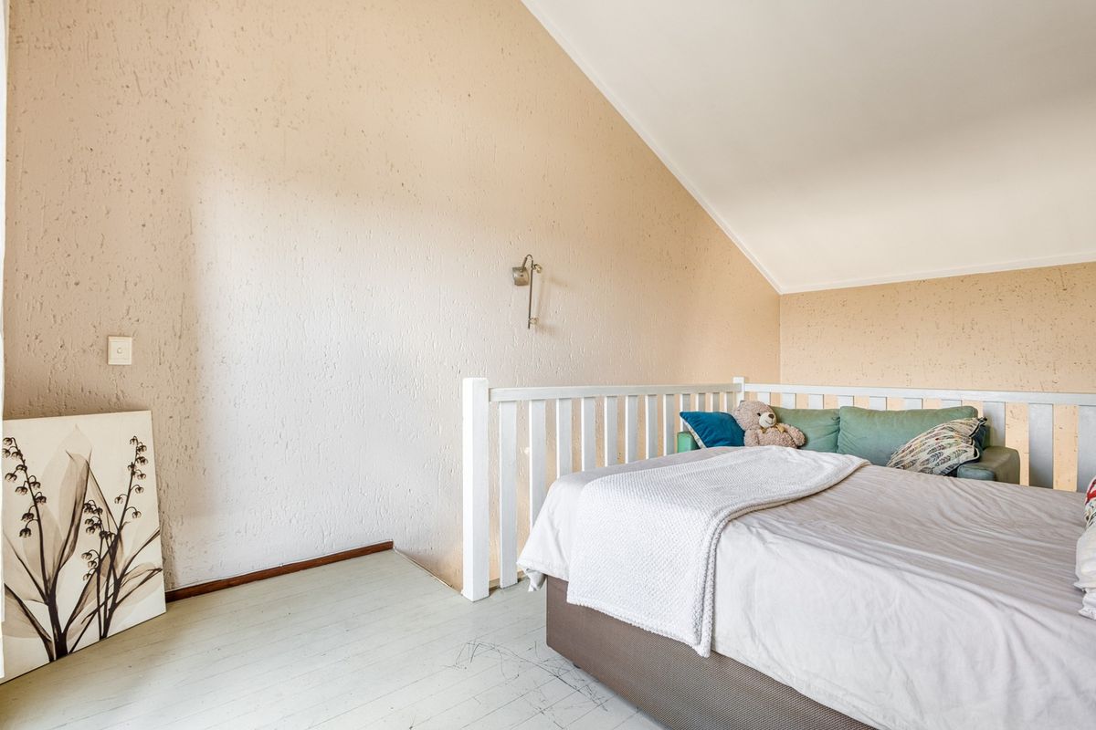 A bedroom featuring a vaulted ceiling, textured walls, and a white wooden balustrade overlooking the lower level.