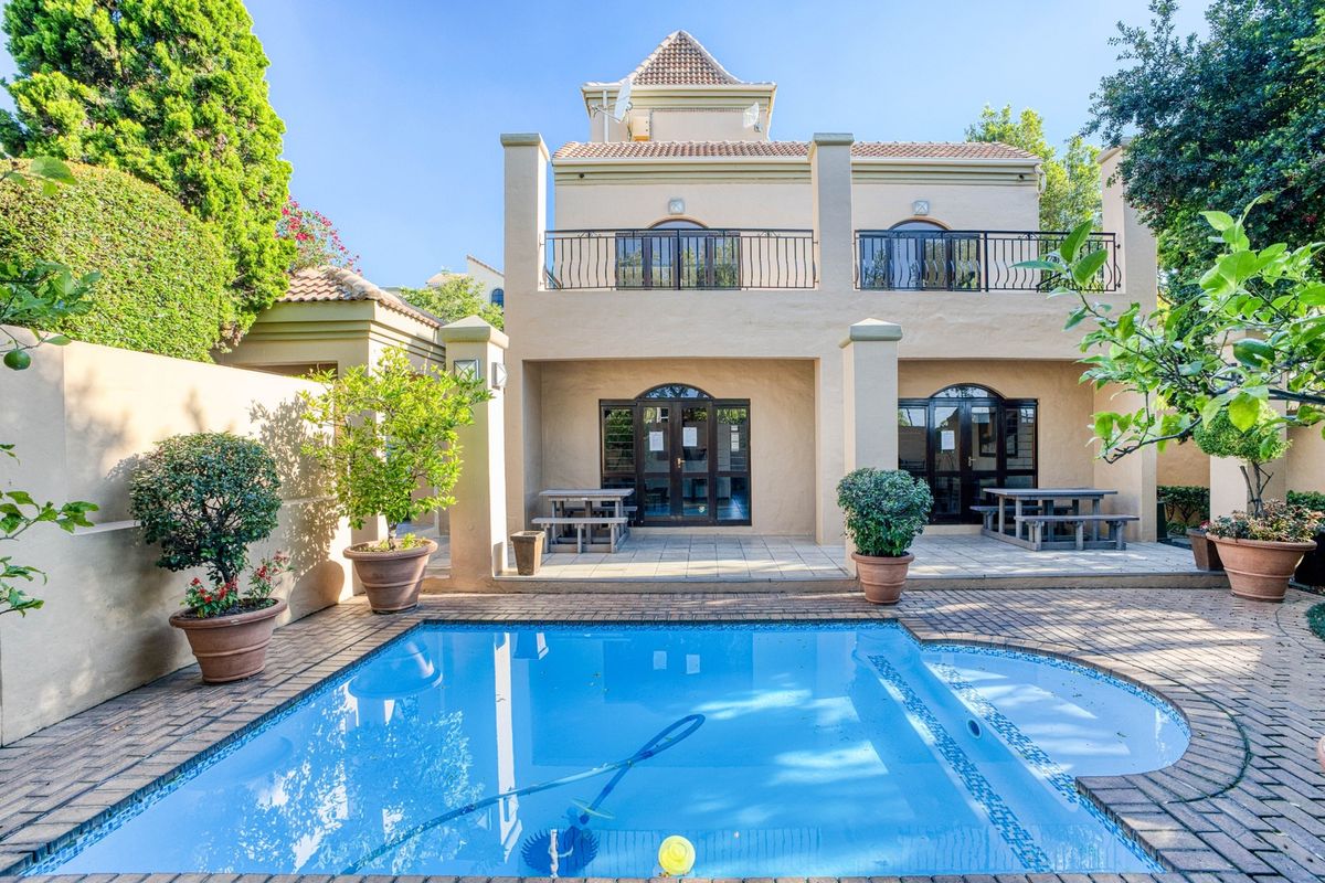 Rear view of the apartment featuring a private swimming pool, paved patio area, and a balcony with wrought iron railings.