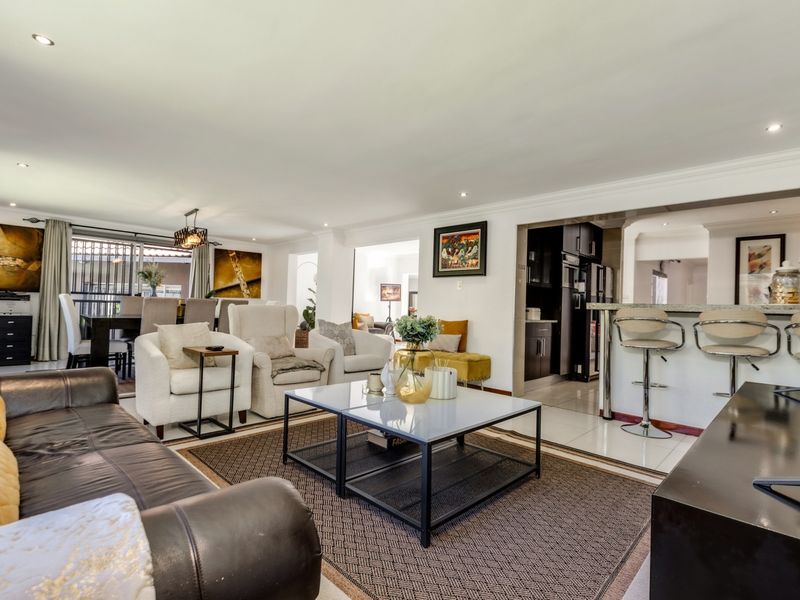 Spacious open-plan living area featuring a breakfast bar, recessed lighting, and tiled flooring, seamlessly connecting the lounge and dining spaces.