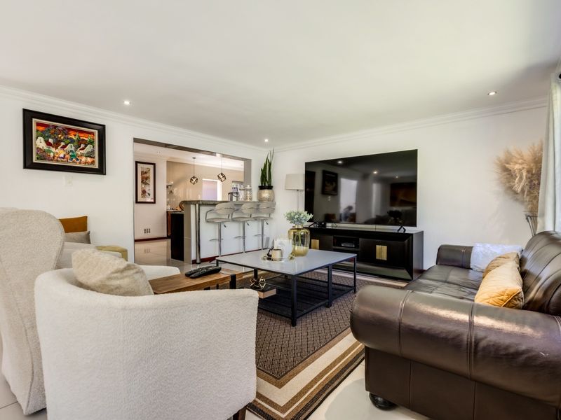 Spacious open-plan living area featuring tiled flooring, recessed downlighting, and a breakfast bar connecting to the kitchen space.