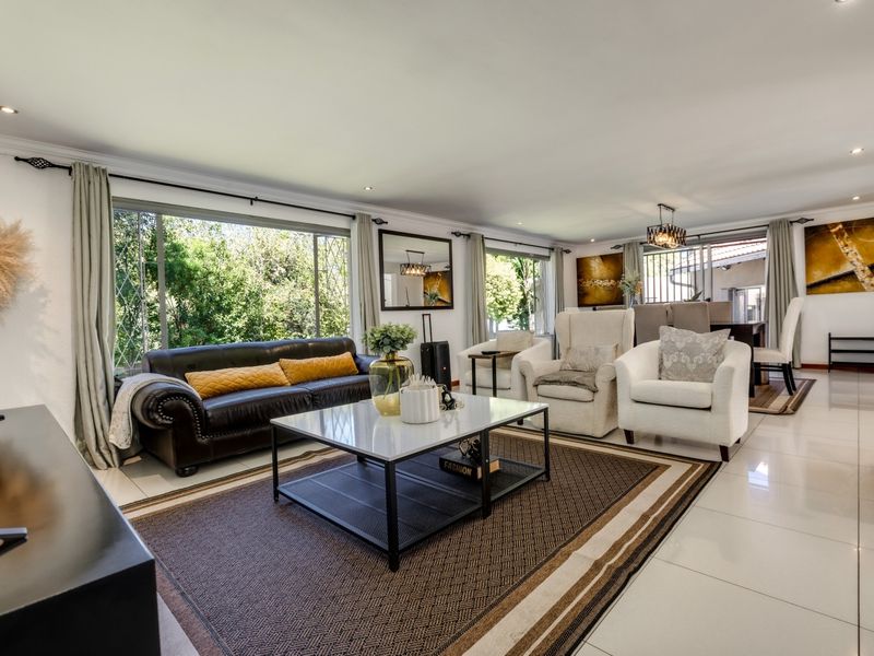 Spacious open-plan living and dining area featuring large windows, recessed downlighting, and neutral tiled flooring throughout.