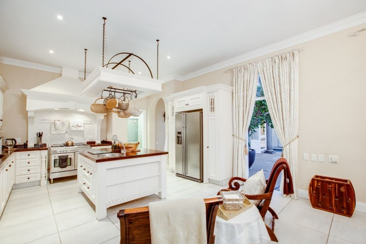 Spacious kitchen featuring a central island, white cabinetry, gas stove with extractor hood, and direct access to an outdoor patio area.