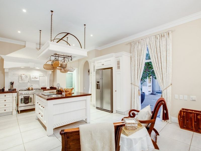 Spacious kitchen featuring a central island, white cabinetry, gas stove with extractor hood, and direct access to an outdoor patio area.