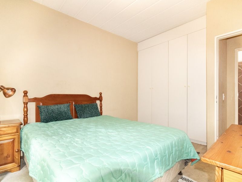 A functional bedroom featuring built-in cupboards and a neutral color palette, offering a comfortable space with direct access to an adjoining bathroom.