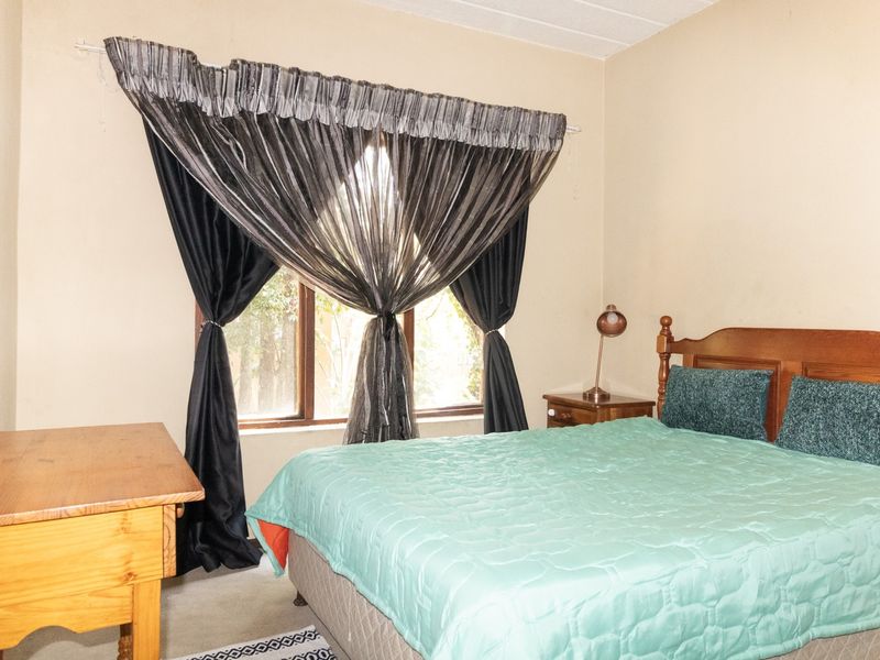 A standard bedroom featuring a window with a curtain rod, providing natural light and a view of the exterior.