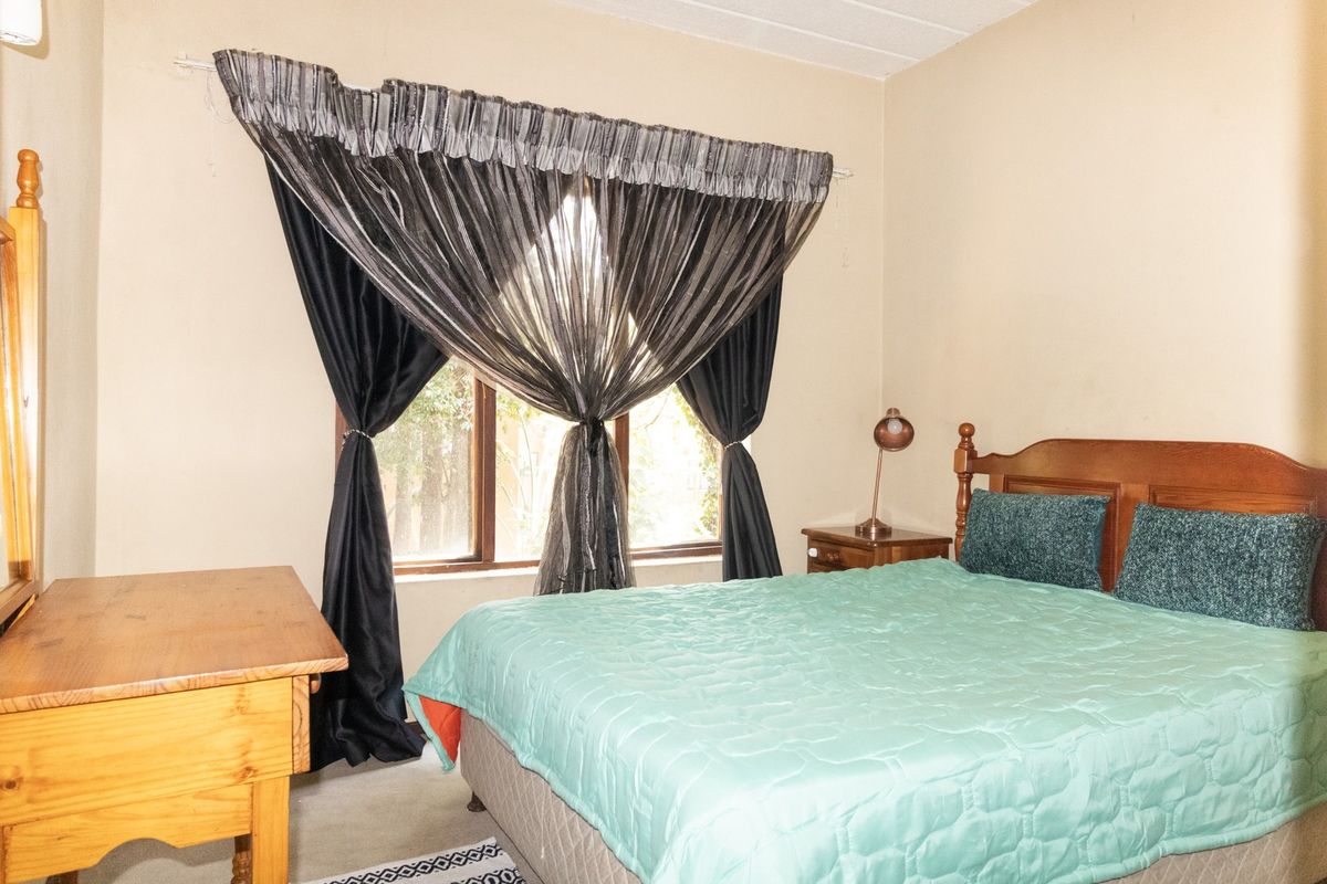 A standard bedroom featuring a window with a curtain rod, providing natural light and a view of the exterior.