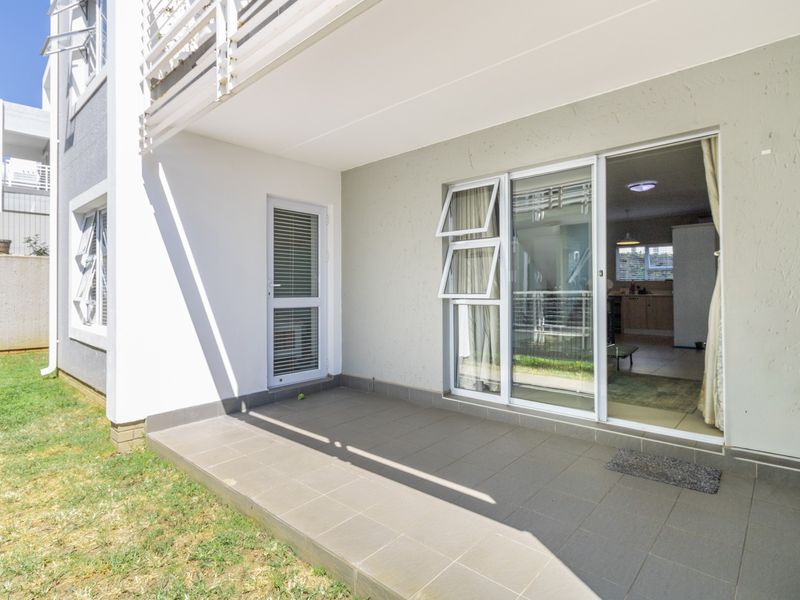 A clean, covered ground-floor patio with tiled flooring, providing direct access to the interior living space through a sliding glass door.
