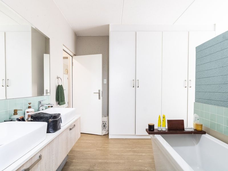 Modern bathroom featuring a double vanity, built-in storage cupboards, and a freestanding bathtub with contemporary tiled finishes.
