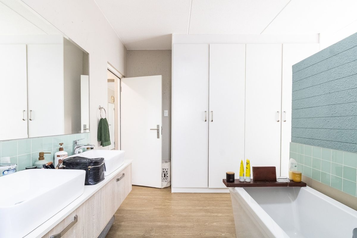 Modern bathroom featuring a double vanity, built-in storage cupboards, and a freestanding bathtub with contemporary tiled finishes.