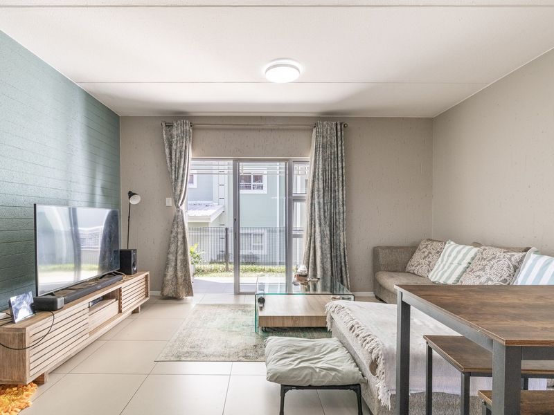 An open-plan living area featuring tiled flooring, an accent wall, and a sliding glass door providing access to the exterior.