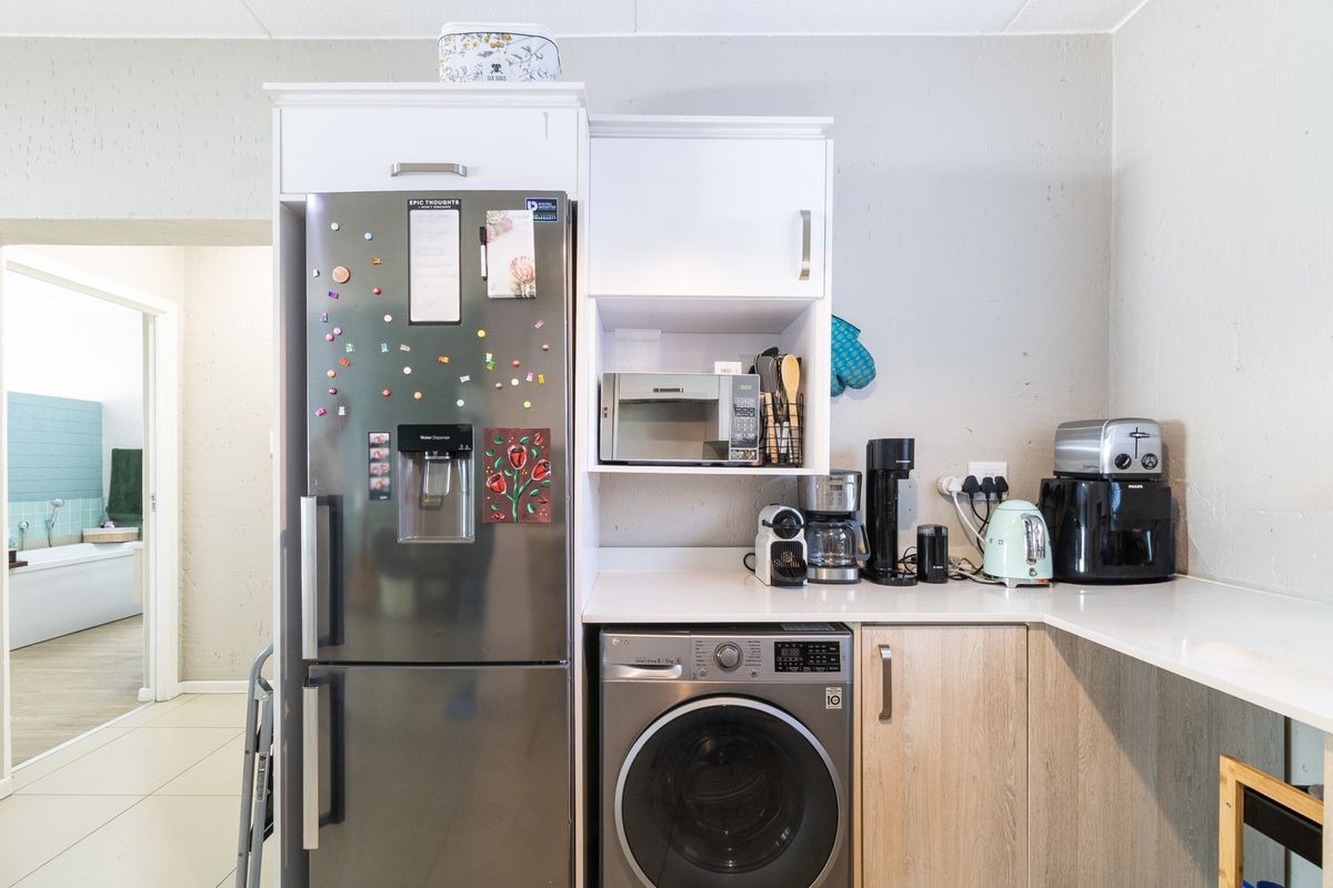 A functional kitchen area featuring built-in cabinetry, a countertop, a built-in microwave, and an integrated washing machine, with a view into the adjacent bathroom.