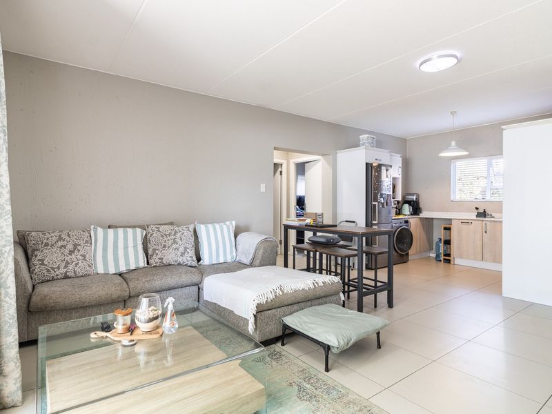 Open-plan living area featuring tiled floors and a functional kitchen space with built-in cabinetry and laundry connections.