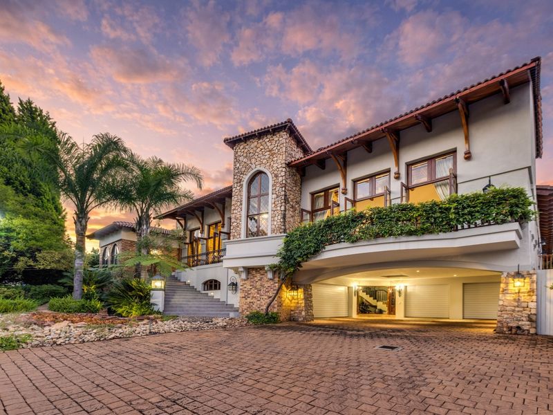 Stunning multi-level residence featuring stone facade detailing, a spacious paved driveway, triple garage, and an elevated balcony overlooking the landscaped front garden.