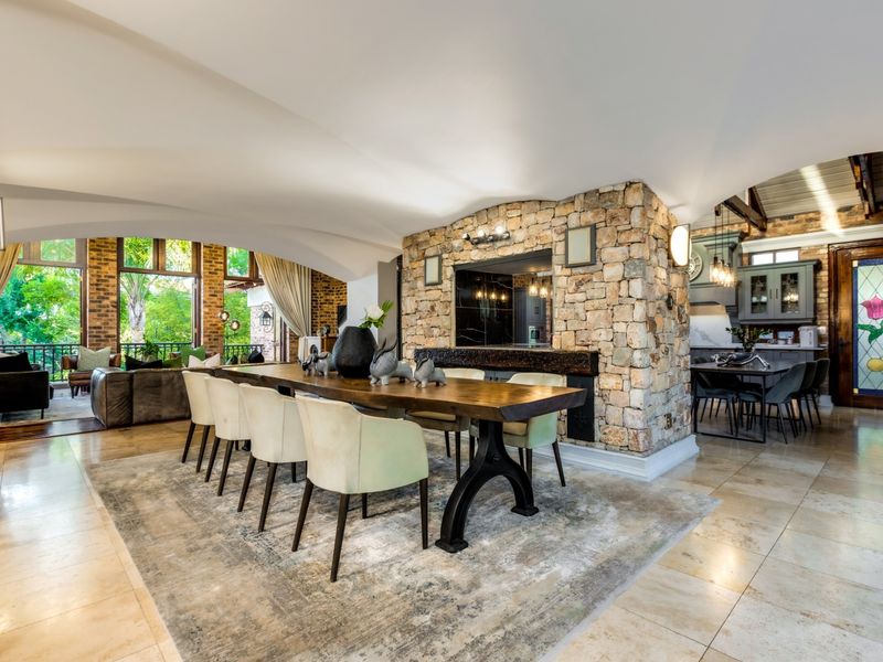 Spacious open-plan living and dining area featuring a striking stone feature wall, vaulted ceilings, and seamless flow to the outdoor patio.